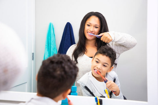mother teaching her son how to brush with Grippi